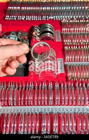 Dall'alto del raccolto l'oculista anonimo che prende a mano gli occhiali da prova il calibro della lente in scatola contenente il set di lenti in clinica oculistica Foto Stock