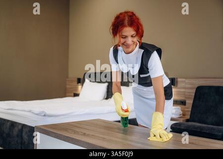 Con guanti gialli, pulire il luogo. La cameriera lavora in una moderna camera d'hotel. Foto Stock