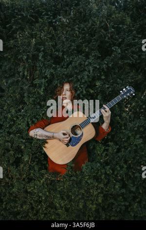 Chitarrista dai capelli rossi con chitarra nel verde Foto Stock
