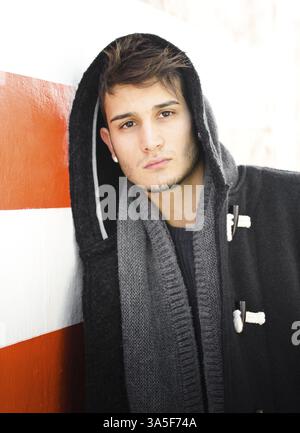 Buona ricerca giovane hoodie contro bianco e arancione parete a strisce Foto Stock