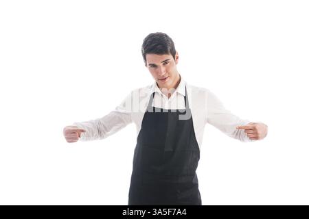 Il giovane chef o il cameriere in posa, indossare un grembiule nero e camicia bianca isolata su sfondo bianco Foto Stock