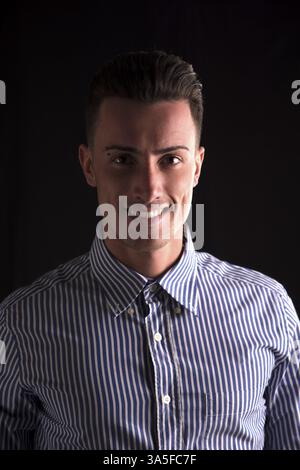 Sorridente Giovane Uomo in camicia a righe, guardando la telecamera, isolato su nero Foto Stock