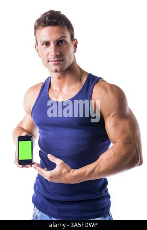 Attraente e muscoloso giovane uomo che mostra il suo cellulare', schermo verde vuoto, isolato su bianco Foto Stock