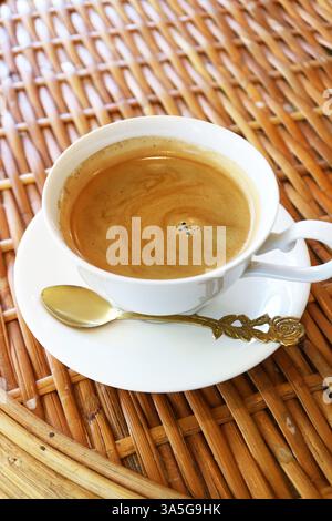 Una tazza di caffè caldo appena fatto isolato sul tavolo di rattan Foto Stock