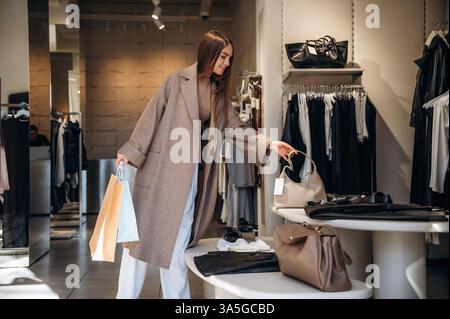 Ho appena visto la borsetta, raccogliendola. La donna sceglie i vestiti in un negozio. Foto Stock