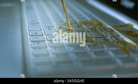 Il tè versato sulla tastiera del laptop causa danni e malfunzionamenti, incidente con liquidi sul dispositivo elettronico, primo piano dei tasti del computer bagnato Foto Stock