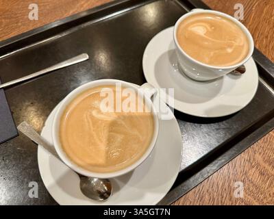 Due tazze di bianco piatto su un vassoio nero Foto Stock