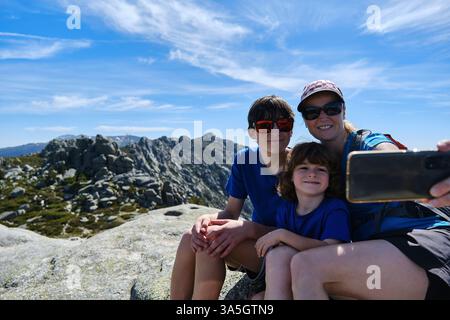 Madre con i suoi figli che si fanno un selfie in montagna Foto Stock