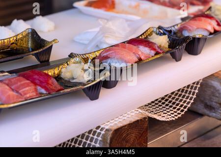 Una selezione di sushi nigiri freschi con tagli di tonno di prima qualità viene servita in vassoi decorativi in un mercato del pesce di Tokyo dove si trovano i sapori tradizionali giapponesi Foto Stock