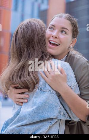 Amici caucasici felici che abbracciano e sorridono all'aperto in un ambiente urbano Foto Stock