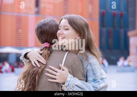 Amici caucasici felici che abbracciano e sorridono all'aperto in un ambiente urbano Foto Stock