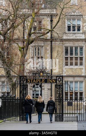 Persone che camminano attraverso cancelli in ferro battuto fino allo Staple Inn di High Holborn, Londra, Inghilterra, Regno Unito Foto Stock