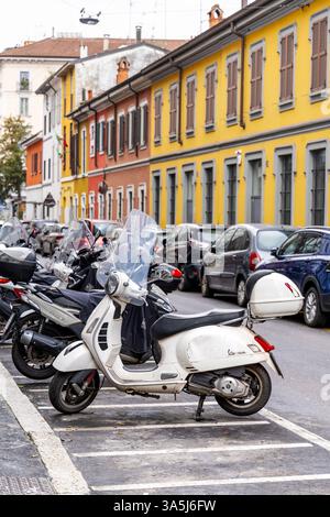 Vespa parcheggiata in via Archimede e case colorate, Milano, Italia Foto Stock