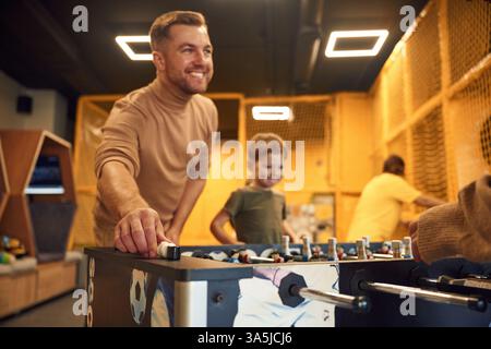 Famiglia di papà, madre e figlio che giocano a biliardo al chiuso. Foto Stock