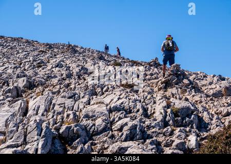 Naxos, Grecia - 2 ottobre 2024: Escursionisti che salgono su un aspro pendio roccioso sul Monte Zeus, la vetta più alta delle Cicladi Foto Stock