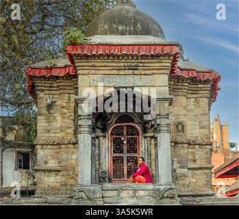 Dunbar Square, Bhaktapur, Nepal - 11 febbraio 2025 - Una donna nepalese sedeva e passava le gambe sui gradini di un tempio Foto Stock
