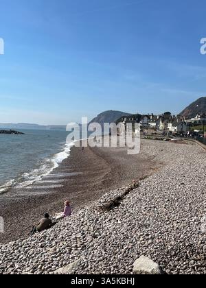 La gente si sedeva sulla spiaggia di Sidmouthin Devon Foto Stock