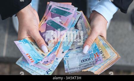 Donna che espone banconote venezuelane bolivar, evidenziando il cambio finanziario Foto Stock
