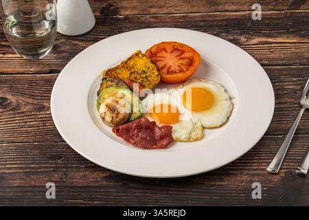 Piatto rustico da colazione con uova fritte, verdure alla griglia e pancetta di tacchino Foto Stock