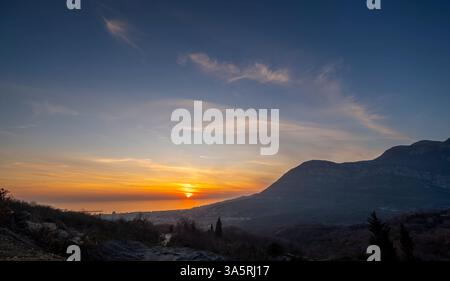 Tramonto vibrante sulle montagne costiere con spettacolari nuvole in un paesaggio sereno Foto Stock