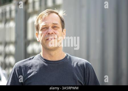 Ritratto di strada di un uomo di 40-50 anni con una t-shirt nera su sfondo neutro sfocato. Forse e' solo un acquirente, un attore o un camionista Foto Stock