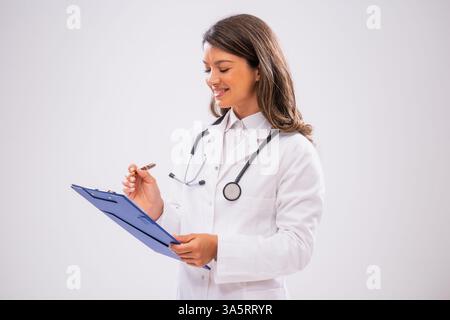 Studio ha scattato un ritratto di una dottoressa felice che tiene in mano gli appunti e scrive. Foto Stock