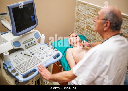 Uomo anziano che ha un esame medico. Il paziente anziano sta effettuando un esame ecografico del suo cuore da parte di un medico esperto. Foto Stock
