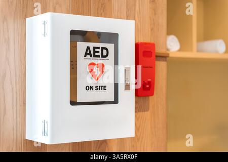 Vista generale di un defibrillatore salvavita. Defibrillatore semiautomatico esterno (AED) portatile montato a parete nei bagni pubblici dell'aeroporto. Foto Stock