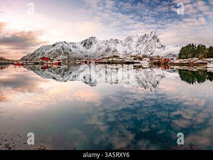 Nuvole sulle cime innevate che si specchiano nel mare Foto Stock