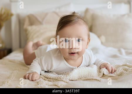 Adorabile bimbo con occhi blu adagiati su un letto confortevole Foto Stock