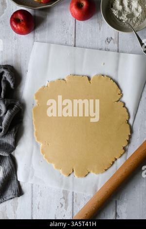 Cuocere la crostata di mele. Impastare su carta da forno e mele rosse Foto Stock