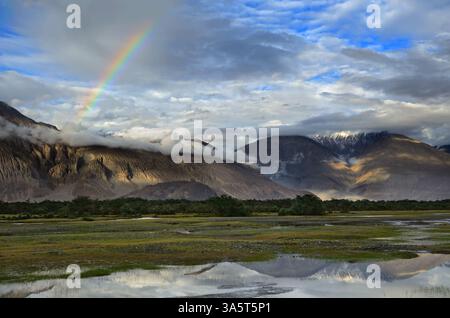 Arcobaleno sulle montagne dell'Himalaya nella valle desertica di Nubra nel Ladakh, India Foto Stock