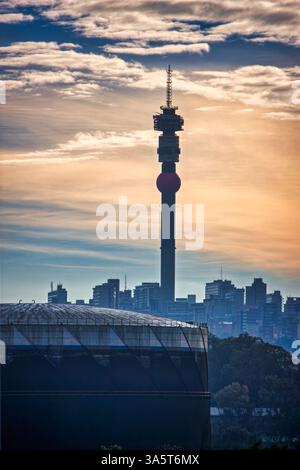 Tramonto sulla torre delle telecomunicazioni di Hillbrow nello skyline della città di Johannesburg. Circondato da edifici del centro di Johannesburg, Sud Africa a Down Foto Stock