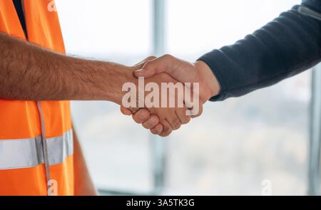 Vista ravvicinata di due lavoratori del cantiere che stringono la mano, incontrate. Foto Stock