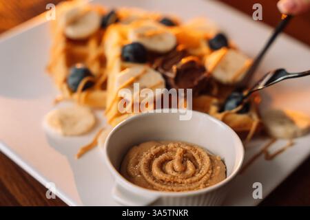 Waffle dolci con banane, paglia e marmellata di bacche a colazione. Foto Stock