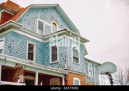La parte superiore della facciata di una casa a tre piani con finiture blu e mattoni da un angolo basso a Philadelphia, Pennsylvania, USA, 23 marzo 2025. Foto Stock