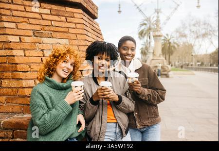 Tre diverse donne turisti si godono la pausa caffè durante il loro tour panoramico di barcellona Foto Stock
