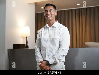 Professionista maschile in piedi con fiducia al ricevimento dell'hotel Foto Stock