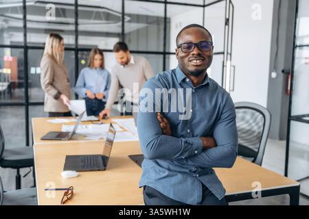 Uomo nero positivo. I lavoratori professionisti si trovano in un ufficio moderno insieme. Foto Stock
