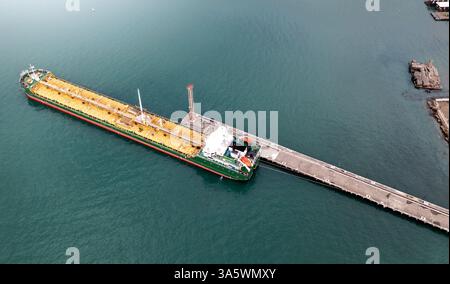 Petroliera ormeggiata presso il molo industriale nel porto marittimo, il trasporto marittimo di combustibile, le infrastrutture logistiche globali, la navigazione offshore e l'industria petrolchimica. Vista aerea dal drone. Foto Stock