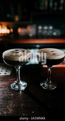 Due bicchieri di bevande miste su un banco bar in legno. Le bevande hanno la forma di una faccia sorridente Foto Stock