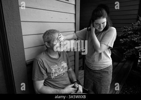 10 giugno 2023, Asheville, Carolina del Nord, Stati Uniti: Josie Klaaren, 22, condivide un momento tenero con suo padre Joshua fuori dalla loro casa di Asheville, NC. Joshua è ansioso per il futuro del suo daughterâ disabile dal punto di vista dello sviluppo, poiché è incontinente e incapace di esprimersi a causa di aprassia. œWho Â si prenderà cura di Josie quando io e sua madre non ci saremo più? Possiamo capire il suo discorso limitato e conosciamo le sue esigenze, ma havenâ siamo stati in grado di trovare o assumere operatori sanitari a domicilio. Nessuno vuole lavorare per i bassi salari che lo stato sta pagando, â ha detto. (Immagine di credito: © Robin Rayne/ZUMA Press Wire) EDITORIALE Foto Stock