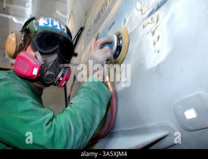 30 giugno 2004; Mar Mediterraneo; Aviation Machinist's Mate 3rd Class Ross Christie attaccato al Fighter Squadron Three Two (VF-32) 'spadaccini' spoglia vecchia vernice da un F/A-18 Hornet nella baia hangar a bordo della USS Harry S. Truman. Truman è una delle sette portaerei che partecipano al Summer Pulse 2004. Summer Pulse 2004 è lo spiegamento simultaneo di sette gruppi di attacco delle portaerei (CSG), dimostrando la capacità della Marina di fornire una potenza di combattimento credibile in tutto il mondo, in cinque teatri con altre forze militari statunitensi, alleate e della coalizione. Summer Pulse è il primo schieramento della Marina Foto Stock