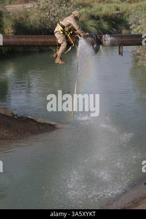 13 novembre 2004; Lutafiyah, Iraq; Seaman CLYNT BIRCH della 24th Marine Expeditionary Unit sigilla le perdite su un tubo rotto con una ruota di scorta e cinghie di carico durante uno sforzo di ricostruzione del ponte a Lutafiyah, Iraq, 13 novembre. Il ponte è stato gravemente danneggiato in ripetuti attacchi da parte di militanti anti anti-iracheni. Birch, 23 anni, è un operatore nativo e costruttore di attrezzature del South Lake, Texas, con il Naval Mobile Construction Battalion 4, assegnato al 24th MEU. Il 24° MEU continua a condurre operazioni di sicurezza e stabilità nella provincia settentrionale di Babil. Foto Stock