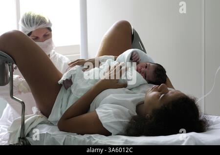 4 luglio 2008 - Rejane Caeira, 18 anni, riceve cure mediche mentre tiene il suo bambino appena nato all'ospedale di maternità Pro Matre di Rio de Janeiro, Brasile. Il Brasile ha un tasso straordinariamente alto di nascite cesaree al 44%, secondo un recente studio del Ministero della salute. Gli esperti affermano che il tasso è dovuto a fattori ''culturali'', nonché a pressioni da parte di ospedali privati, che devono giustificare gli investimenti in tecnologia. In un recente studio pubblicato nel numero di giugno 2008 di Ostetricia e Ginecologia, il parto cesareo è stato associato ad un aumentato rischio di complicazioni in una gravidanza successiva. (Dougla Foto Stock