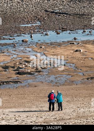 La coppia senior consulta la mappa sulla spiaggia vestita con abiti da passeggio. Foto Stock
