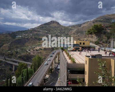 Veduta aerea di un'autostrada e di un edificio nella città di Taormina, situato sulla cima di una collina conosciuta per l'antico teatro greco-­Roman che è il Foto Stock
