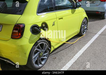 Auto elettrica gialla Fiat Abarth presso un punto di ricarica per il rifornimento di carburante elettrico possiamo anche vedere una ricarica Leapmotor Foto Stock