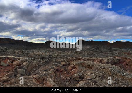 Paesaggio vulcanico caratterizzato da un vasto campo di lava che emette vapore in Islanda, sullo sfondo di cieli spettacolari e nuvolosi Foto Stock