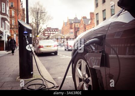 Londra - Parcheggio per auto elettriche in una strada urbana di lusso con cavo di ricarica Foto Stock